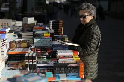 Una dona mira llibres en una parada de la Rambla. 