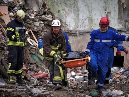 Los servicios de emergencia trasladando un cuerpo sin vida en uno de los edificios de Kiev atacados por Rusia, este viernes.