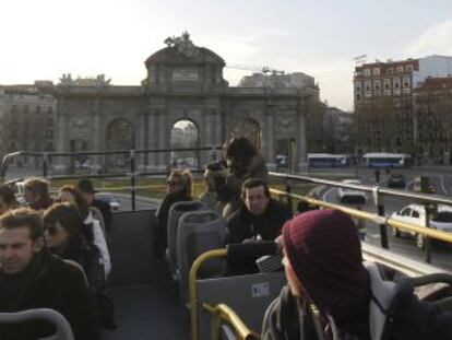 Un grupo de visitantes en un autobús turístico en Madrid, a su paso por la Puerta de Alcalá.
