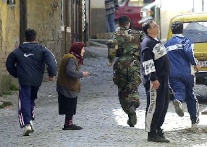 Vecinos de Tetovo corren, junto a un policía especial, para resguardarse de los disparos de un francotirador.