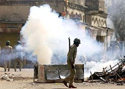Un policía indio pasa ante los destrozos ocasionados por extremistas hindúes en Ahmedabad.