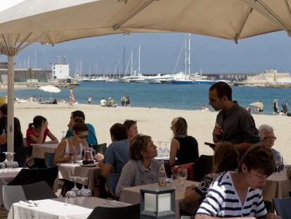 Turistas en una terraza frente al mar en Barcelona