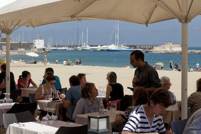 Turistas en una terraza frente al mar en Barcelona