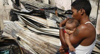 Un hombre con su bebé, entre los materiales recuperados después de un incendio en en Manila (Filipinas).