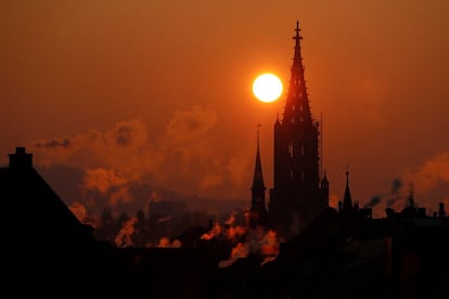 El sol se levanta detrás de la Catedral de Münster durante una mañana fría en Berna (Suiza).