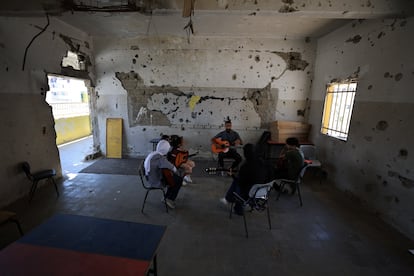 En el Gaza College, una escuela en Ciudad de Gaza, tres niñas y un niño asisten a una clase de guitarra con el profesor Mohammed Abu Mahadi en un aula con las paredes marcadas por las cicatrices de la metralla y las ventanas destrozadas, el pasado 6 de agosto. Son parte del Conservatorio Nacional de Música Edward Said donde 12 profesores, imparten clases a 600 alumnos en el sur y el centro de la Franja de Gaza, en medio del horror de la guerra. El maestro Mahadi cree que la música puede ayudar a los palestinos a recuperarse psicológicamente del dolor causado por los bombardeos, las pérdidas y la escasez.
