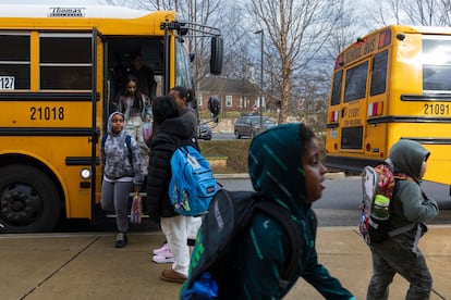 Rock Creek Forest Elementary School students exit a diesel bus before attending school, Friday, Feb. 2, 2024, in Chevy Chase, Md. At right is an electric school bus.