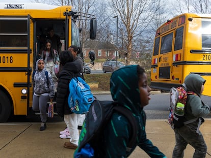 Rock Creek Forest Elementary School students exit a diesel bus before attending school, Friday, Feb. 2, 2024, in Chevy Chase, Md. At right is an electric school bus.