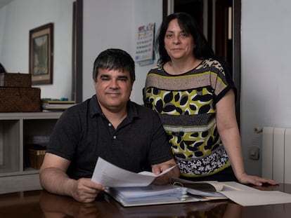 Cristina Calderón y Joan Manel Argüelles, en el salón de su casa, en Barcelona, con la documentación de su adopción.