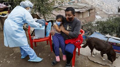 Fotografía de archivo fechada el 30 de julio de 2020, que muestra a una enfermera de la posta médica del Cerro El Agustino mientras coloca una vacuna contra la neumonía a una niña que vive en las zonas altas del cerro, en Lima (Perú).
