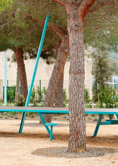 La mesa comunal serpentea entre los pinos existentes en el parque, de los que obtiene sombra.