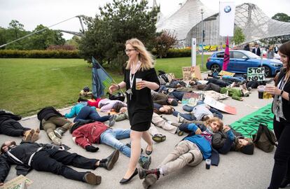 Varias empleadas de la Junta General de Accionistas del fabricante de vehículos BMW ofrecen bebidas a los manifestantes concentrados a las puertas durante la celebración de la reunión en Múnich (Alemania), este jueves. 