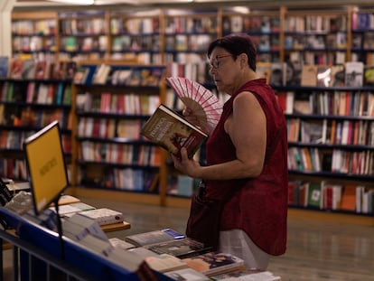 Una clienta mira libros mientras se abanica en la cooperativa Abacus, en Barcelona.