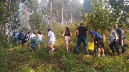 Los vecinos de Moaña (Pontevedra) repelen el fuego a las puertas de sus casas, este domingo por la tarde.