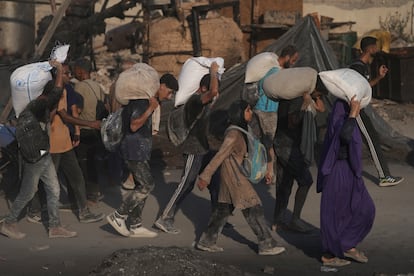Varios palestinos cargan sacos de harina descargados de un convoy de ayuda humanitaria, este sábado en Ciudad de Gaza.