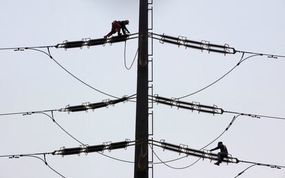 Trabajadores de la empres K-Electric comprueban los cables en una torre de alta tensión en Karachi (Pakistán). 
