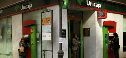 Varias personas utilizan cajeros de una oficina de Unicaja.