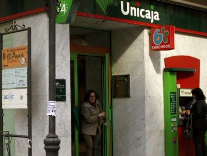 Varias personas utilizan cajeros de una oficina de Unicaja.
