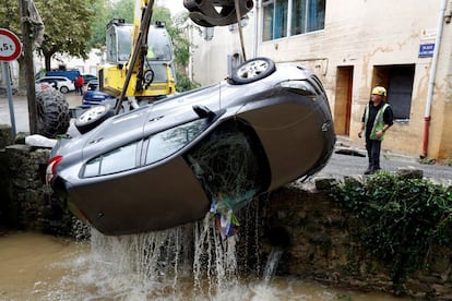Un hombre trata de recuperar un coche semihundido en un río con una excavadora tras las inundaciones en Villegailhenc (Francia).