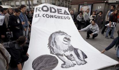 Unos jóvenes despliegan en la Puerta del Sol de Madrid un cartel con el lema "Rodea en Congreso".