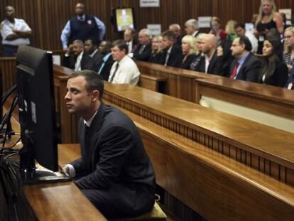 Oscar Pistorius se sienta en el banquillo minutos antes de que comience su juicio en Pretoria. 