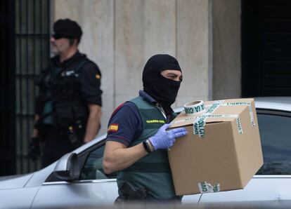 A Civil Guard officer takes away material seized from a home in Sabadell.