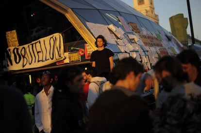 Un joven junto a la entrada del metro y del tren de cercanias de la Puerta del Sol observa el amanecer esta mañana.