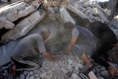 Varios hombres buscan supervivientes entre los escombros de un edificio colapsado en un ataque israelí en Rafah, este viernes.
