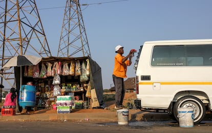 Un hombre lava su taxi junto a un puesto informal de venta de alimentos en Soweto, Sudáfrica, durante el confinamiento por covid-19 en septiembre de 2020.