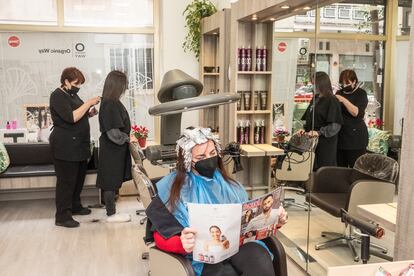 Una clienta se seca el pelo después de aplicarse un tratamiento "babylight", en la peluquería Mariola Sánchez, ubicada en el centro de Madrid.