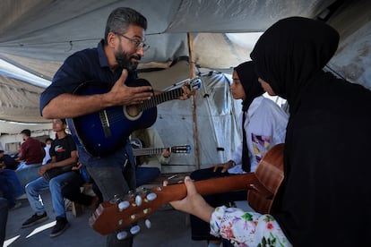 Ahmed Abu Amsha [en la fotografía], profesor de guitarra y violín, fue uno de los primeros que comenzó a impartir clases de nuevo, tocando la guitarra por las tardes entre las tiendas de campaña de los desplazados en el sur de Gaza, donde gran parte de los 2,1 millones de habitantes fueron obligados a trasladarse por las órdenes de evacuación y los bombardeos israelíes. Tras el inicio del alto el fuego en enero, Abu Amsha, de 43 años, fue una de las miles de personas que regresaron a Ciudad de Gaza. Durante los últimos seis meses, ha estado viviendo y trabajando en el distrito central de la ciudad, junto con colegas que enseñan oud, guitarra, tambores de mano y ney, una flauta de caña.
