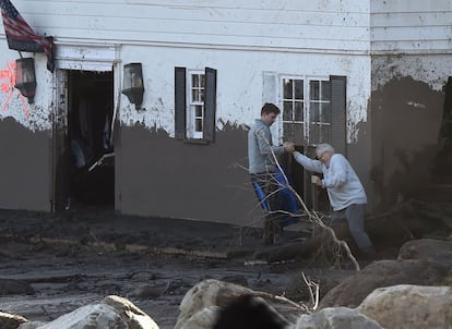 Dos hombres intentan entrar en su casa, inundada de barro, en Montecito, California, el 10 de enero de 2018. 