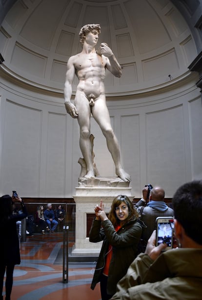 Una mujer posa delante de la escultura del  David de Miguel Ángel, en Florencia (Italia).