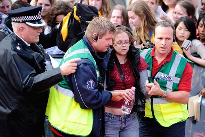 Algunos de los fanáticos necesitaron de cuidado médica tras ser sobrecogidos por la euforia y el llanto. En la imagen una joven es asistida por paramédicos y retirada de la multitud.