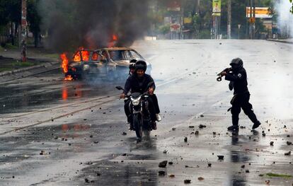 Un policía dispara a dos hombres durante las protestas contra el presidente de Nicaragua Daniel Ortega, en Managua.