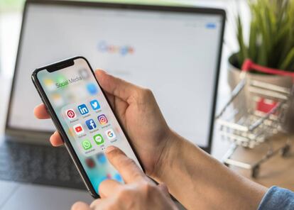 Una persona sostiene un móvil, donde se pueden observar varias aplicaciones informáticas como Twitter. GETTY IMAGES