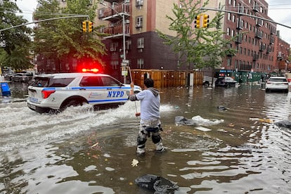 A man works to clear a drain in flood waters, Friday, Sept. 29, 2023, in the Brooklyn borough of New York