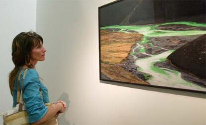 Una visitante observa una de las fotografias de la exposición <i>Caminos de Naturaleza</i>, que propone un recorrido por la obra fotográfica del danés Olafur Eliasson.
