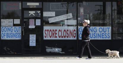 Una mujer pasa frente al escaparate de un comercio cerrado el pasado miércoles en Niles (Illinois). En vídeo, la pérdida de empleo golpea a EE UU.