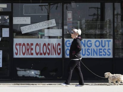 Una mujer pasa frente al escaparate de un comercio cerrado el pasado miércoles en Niles (Illinois). En vídeo, la pérdida de empleo golpea a EE UU.