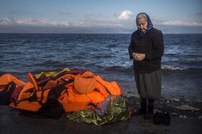 Una mujer junto a una pila de chalecos salvavidas abandonados tras la llegada de un grupo de inmigrantes, en una playa de la isla griega de Lesbos.