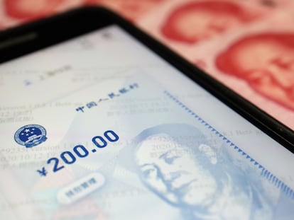 Imagen de la aplicación del yuan electrónico junto con un billete en efectivo.