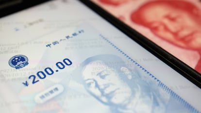 Imagen de la aplicación del yuan electrónico junto con un billete en efectivo.