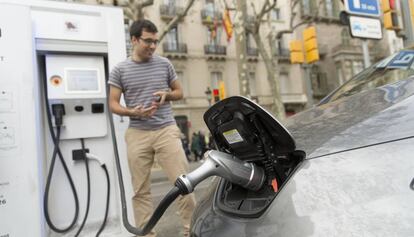 Un conductor carga su coche el&eacute;ctrico.