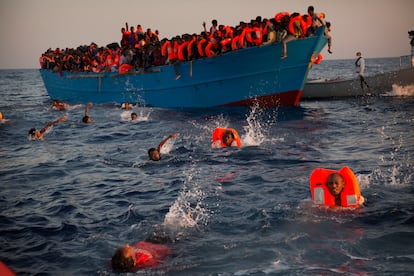 In this file photo from Aug. 29, 2016 migrants, most of them from Eritrea, jump into the water from an overcrowded wooden boat as they are helped by NGO members during a rescue operation in the Mediterranean Sea, about 13 miles north of Sabratha, Libya. 