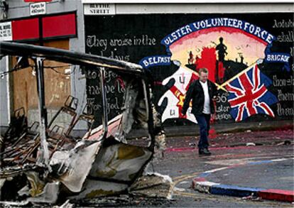 Un hombre pasa ante los restos de un autobús incendiado esta noche en Belfast.