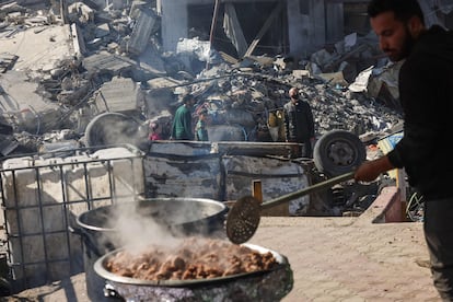 Un palestino cocina junto a los escombros de varios edificios destruidos tras los bombardeos israelíes en una calle de Rafah, este jueves. 