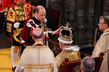 El príncipe Guillermo toca la corona de su padre, el rey Carlos III, durante la ceremonia.