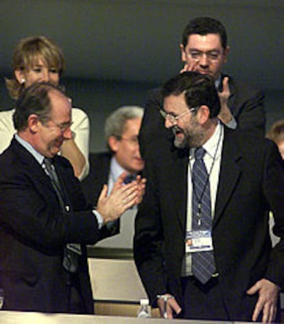 Rodrigo Rato aplaude a Mariano Rajoy tras la intervención de éste.