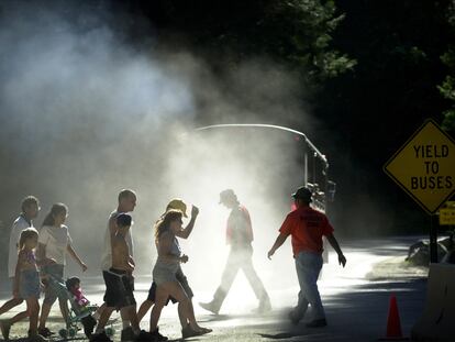 Los peatones caminan a través de una nube de polvo y gases de escape de diésel de un autobús en California (EE UU).